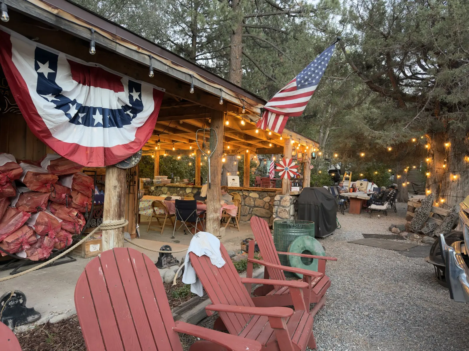 The pavilion's covered patio at dusk — string lights on, the long tables full.